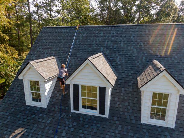 a man is cleaning the roof of a house with a vacuum cleaner .