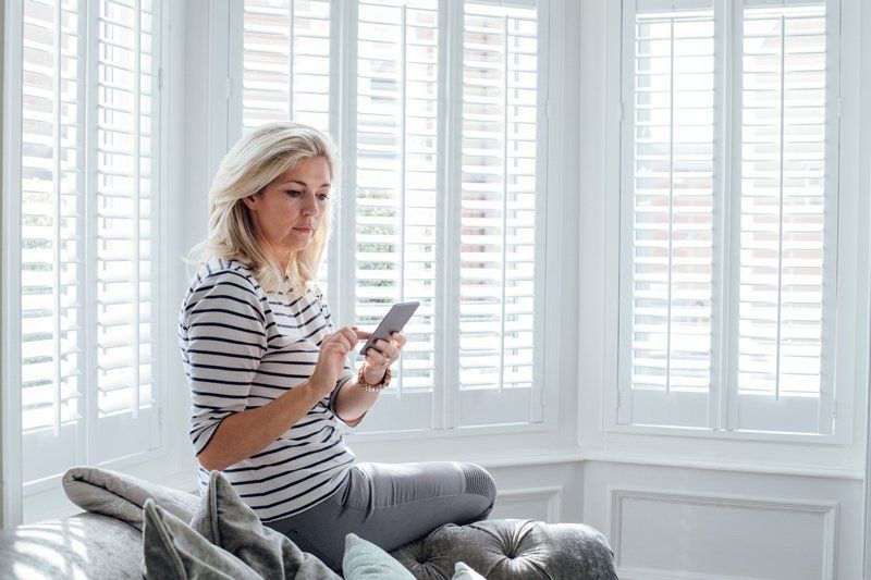 Woman Using Phone — Denham Springs, LA — Blinds By Tones & Textures