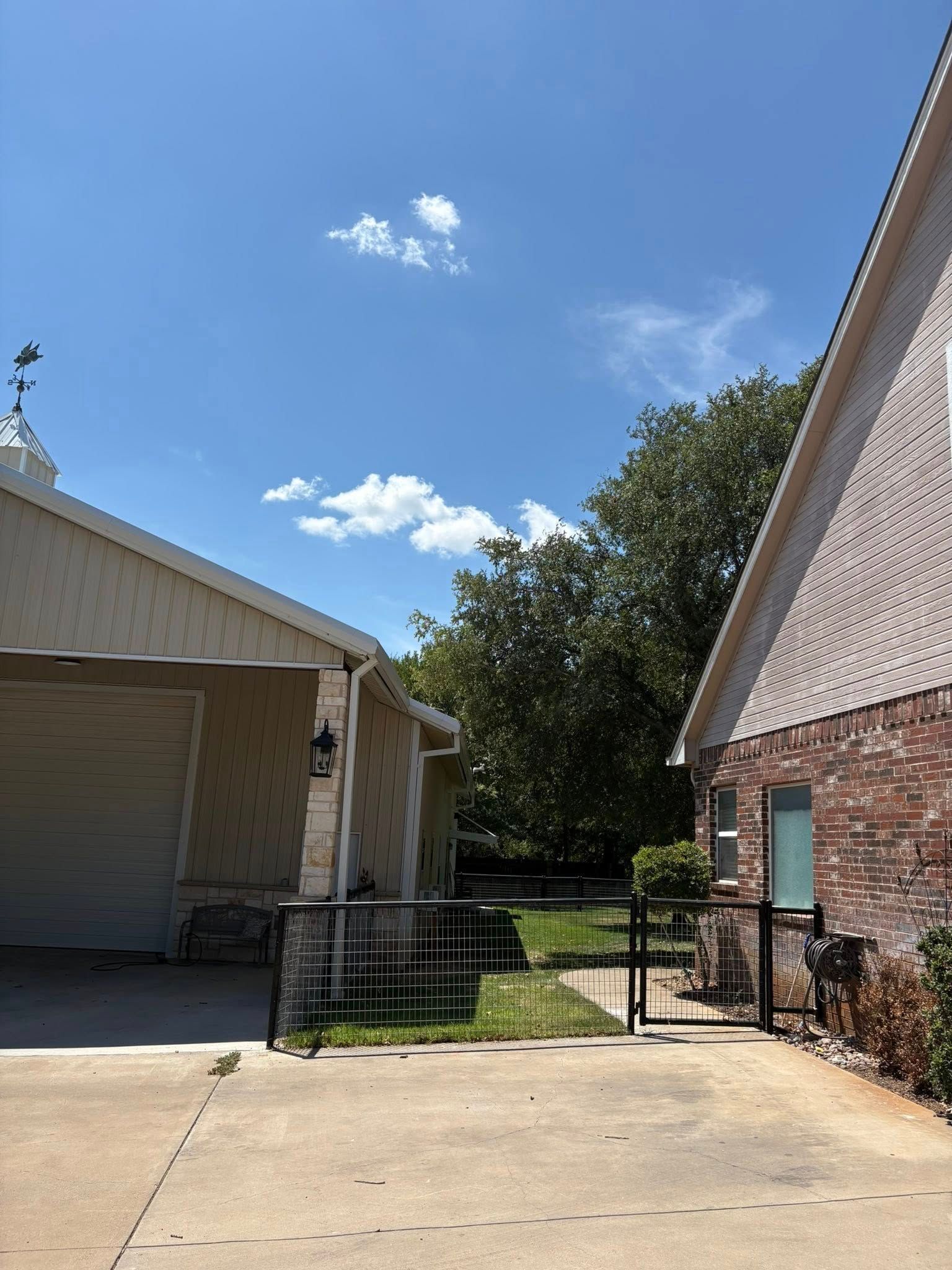 Buildings and metal fence on a sunny day with blue sky and some clouds.