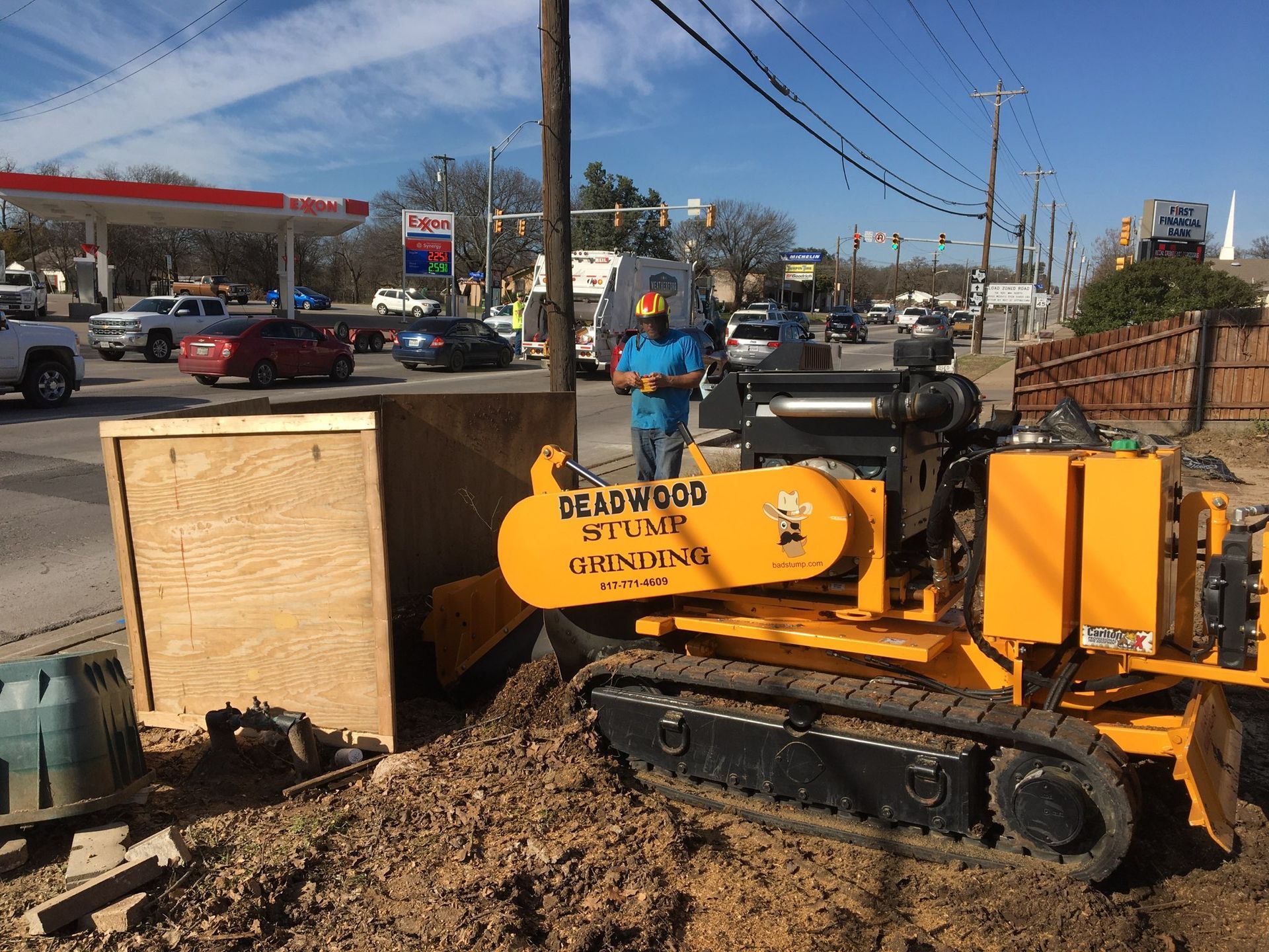 A yellow stump grinder working next to a road, with a person operating it.