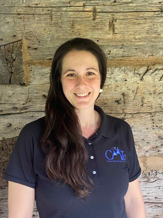 Owner of Boone NC cleaning company is smiling in front of a wooden wall.