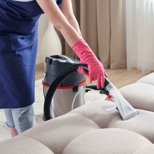 Best carpet cleaning services Boone NC employee is cleaning a couch with a vacuum cleaner.