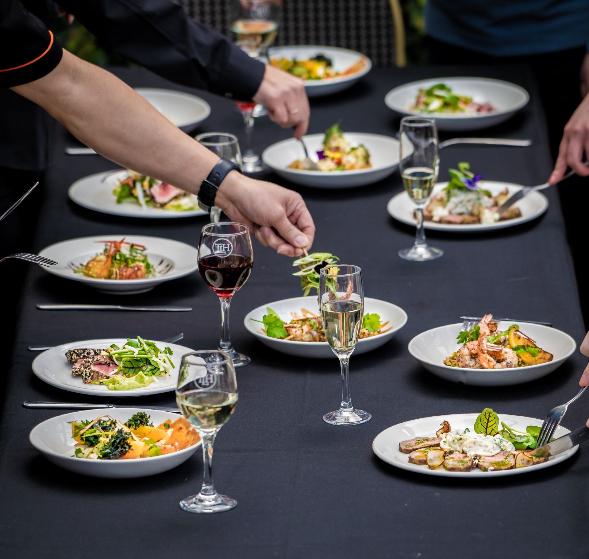 People at a table enjoying a meal with various dishes, wine, and champagne.