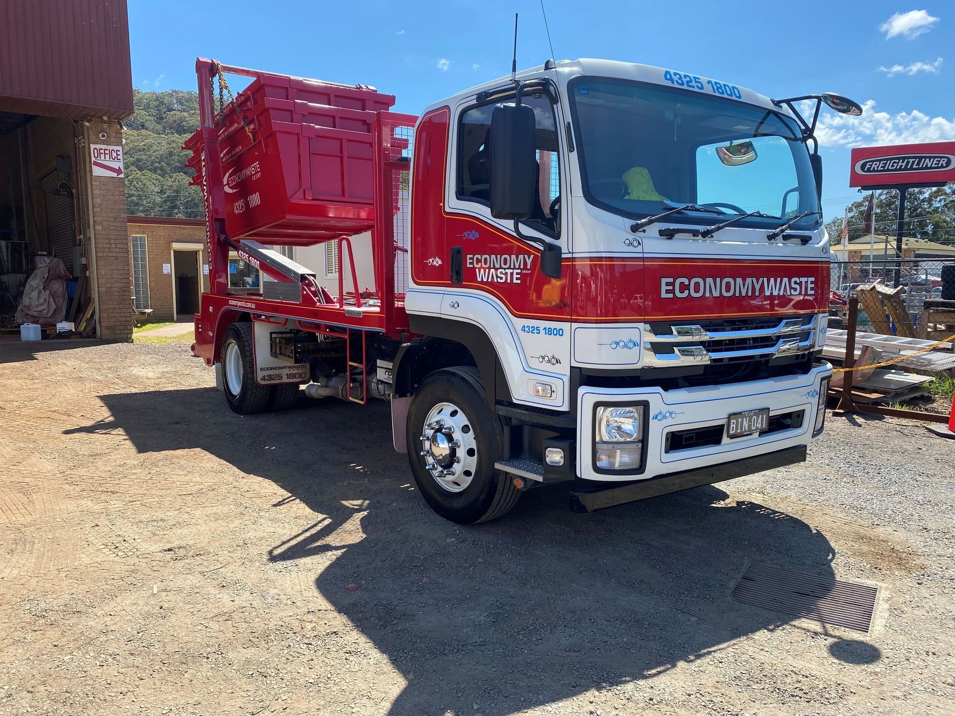 A Red And White Dump Truck Is Parked In A Dirt Lot — Economy Waste Group | Skip Bins Central Coast In Woy Woy, NSW