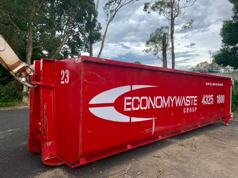 A Red Dumpster With The Word Economy Waste On It — Economy Waste Group | Skip Bins Central Coast In Chittaway Bay, NSW