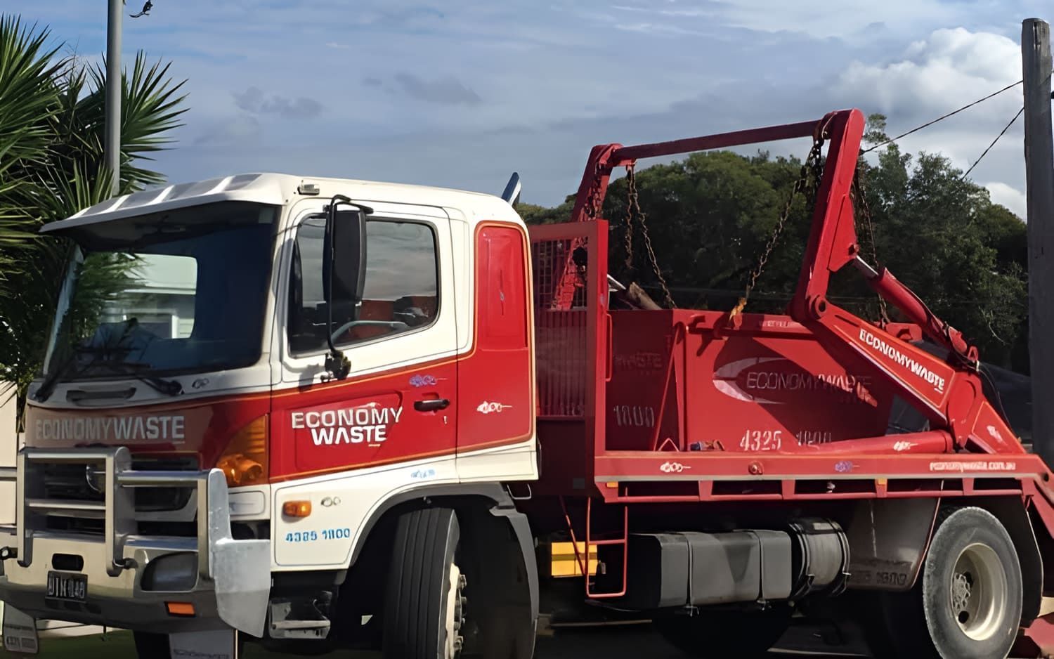 A Red And White Dump Truck Is Parked On The Side Of The Road — Economy Waste Group | Skip Bins Central Coast In Erina, NSW