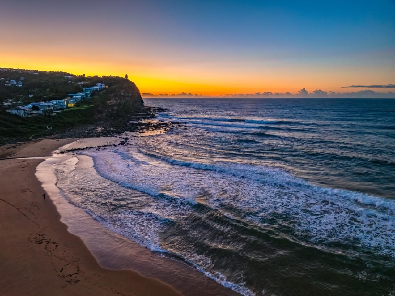 An Aerial View Of A Beach At Sunset With Waves Crashing On The Shore — Economy Waste Group | Skip Bins Central Coast In Copacabana, NSW