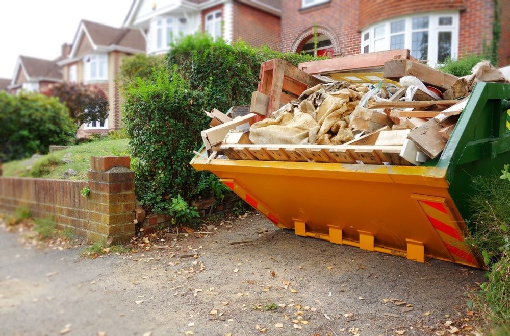 A Dumpster Filled With Junk Is Parked In Front Of A House — Economy Waste Group | Skip Bins Central Coast In Gosford, NSW
