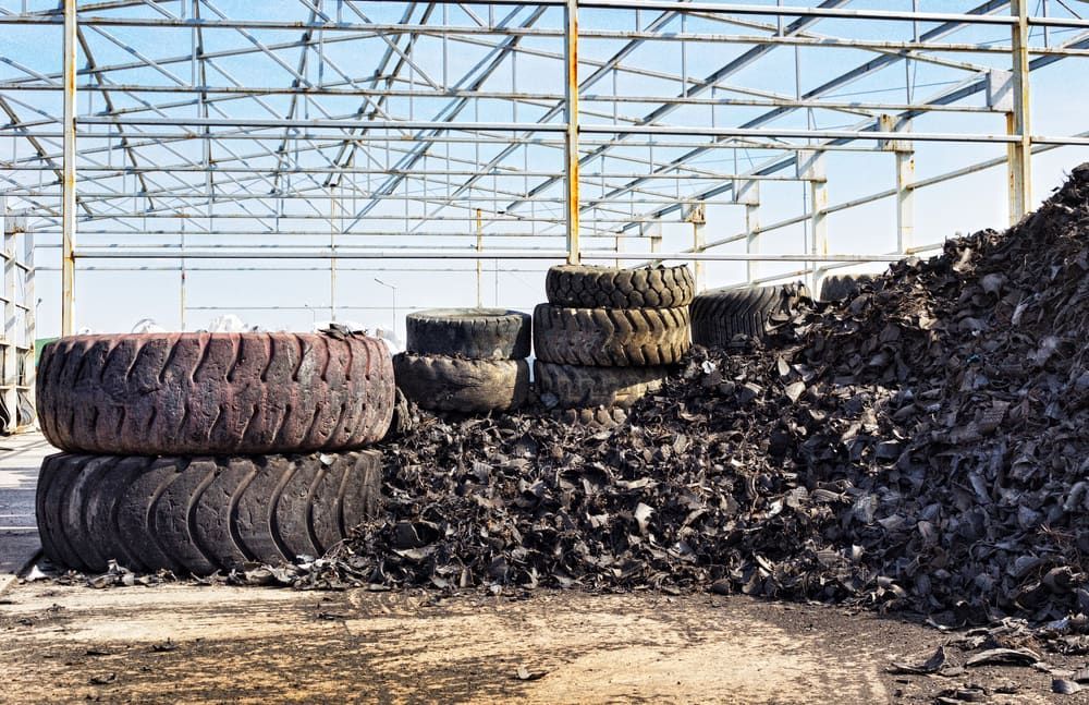 A Pile Of Tires Stacked On Top Of Each Other In A Warehouse — Economy Waste Group | Skip Bins Central Coast In Saratoga, NSW