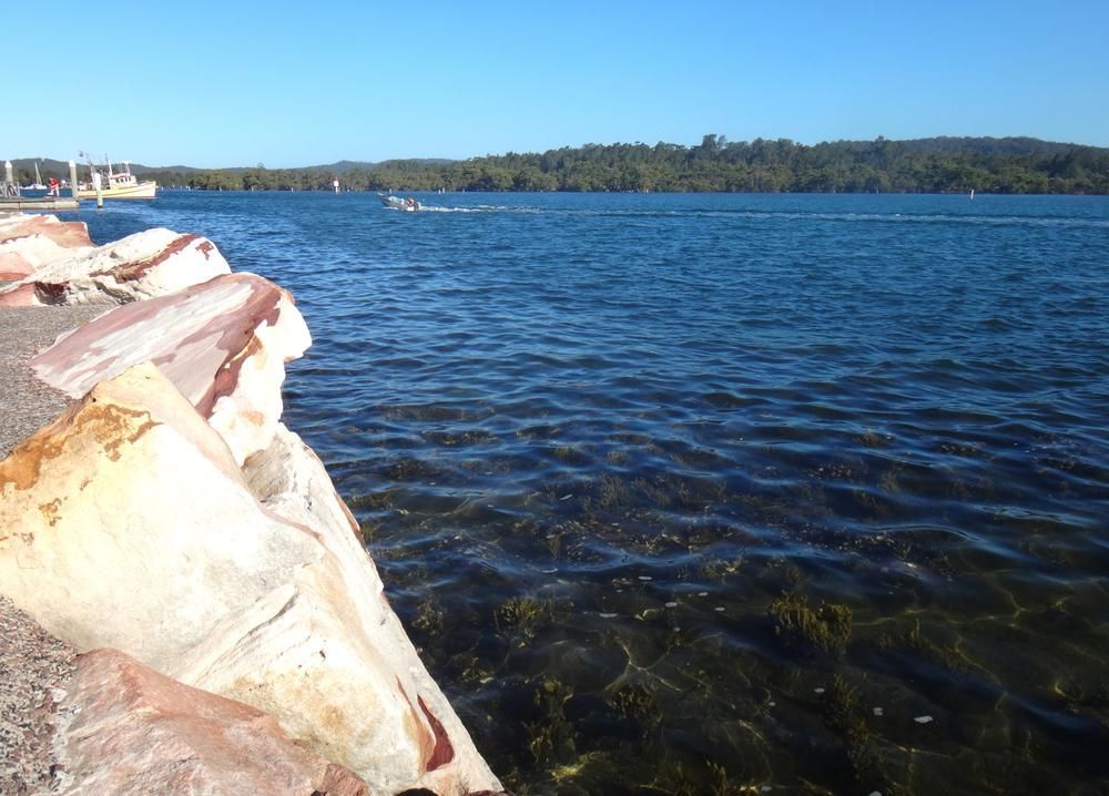 A Large Body Of Water With A Boat In The Distance — Economy Waste Group | Skip Bins Central Coast In Saratoga, NSW