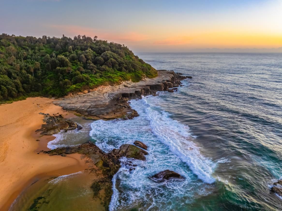 An Aerial View Of A Beach With Waves Crashing Against The Rocks At Sunset — Economy Waste Group | Skip Bins Central Coast In Wamberal, NSW