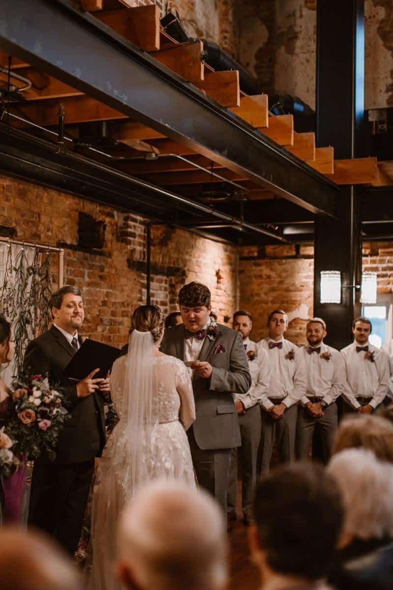 A bride and groom are getting married in front of a crowd of people.