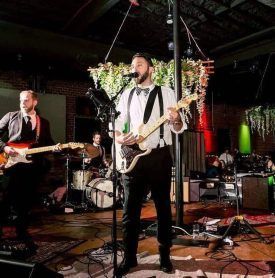 A man is playing a guitar and singing into a microphone on stage.