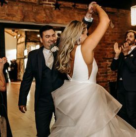 A bride and groom are dancing with their guests at their wedding reception.