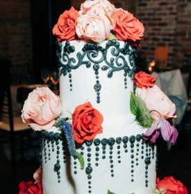 A three tiered wedding cake decorated with roses and leaves.