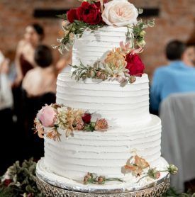 A three tiered wedding cake with flowers on top of it.