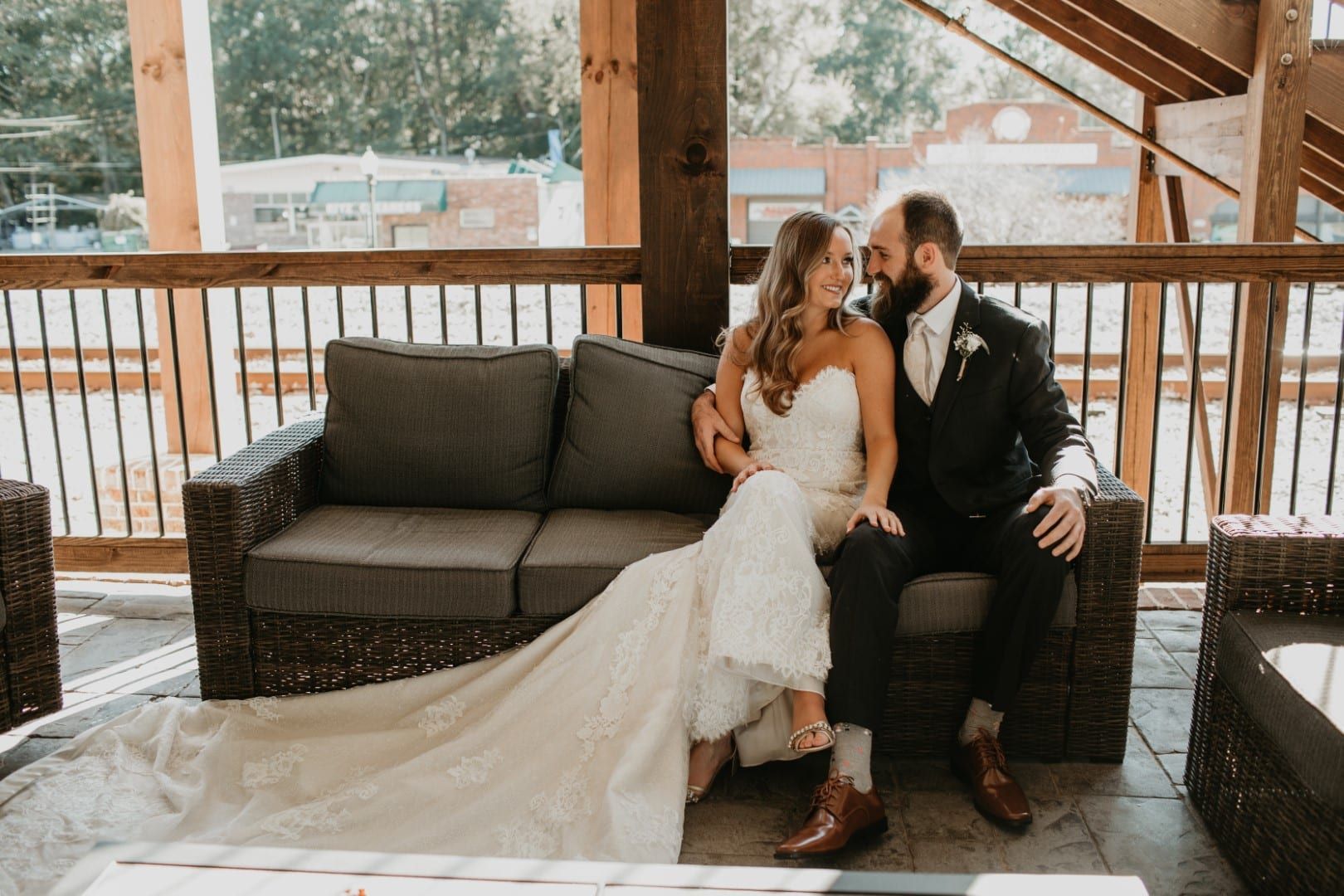 A bride and groom are sitting on a couch on a balcony.