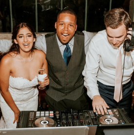 A bride and groom are posing for a picture with a dj