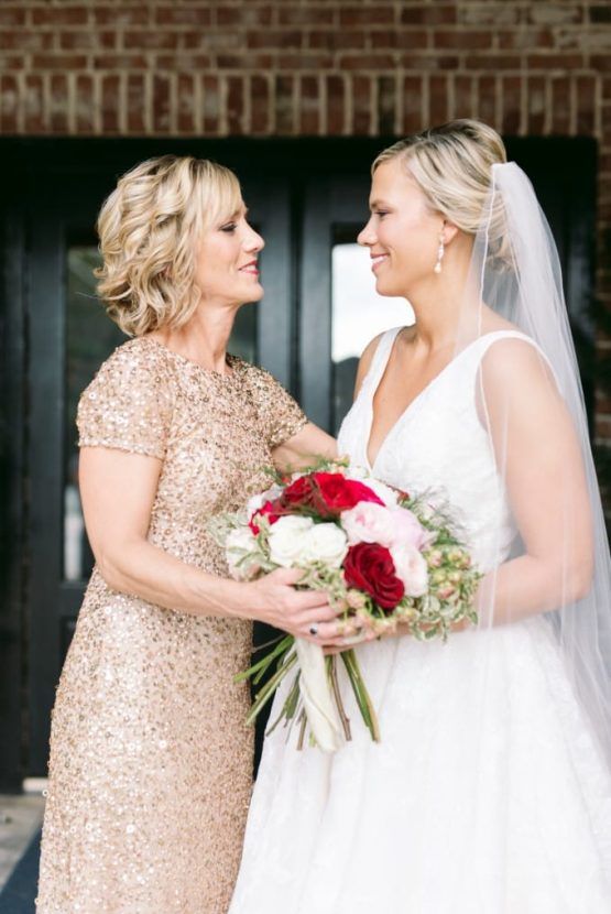 A bride and her mother are standing next to each other holding a bouquet of flowers.