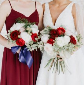 A bride and her bridesmaid are holding bouquets of flowers.