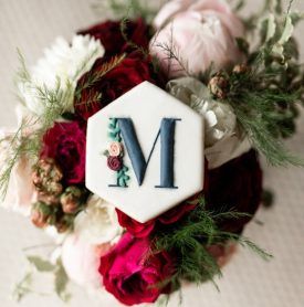 A bouquet of flowers with a cookie with the letter m on it.