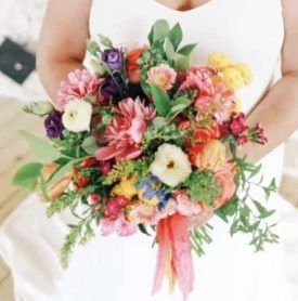 A woman in a white dress is holding a bouquet of flowers.