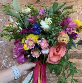 A person is holding a bouquet of flowers in front of a brick wall.