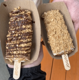 A person is holding two popsicles with the word joobar on them