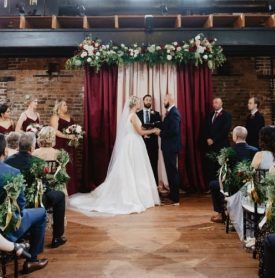 A bride and groom are standing in front of a crowd at a wedding ceremony.