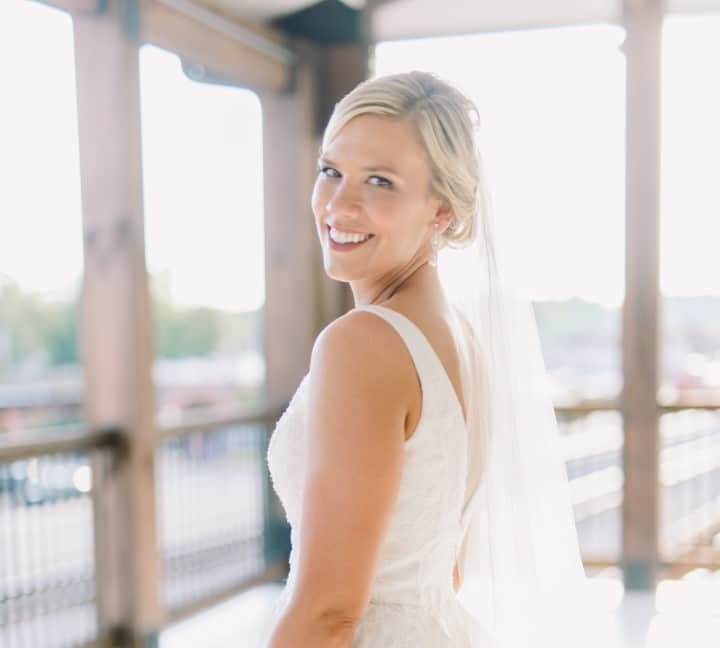 The bride is wearing a veil and smiling for the camera