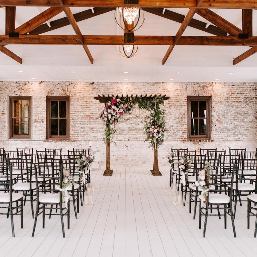 A room with rows of chairs and a wooden arch decorated with flowers.