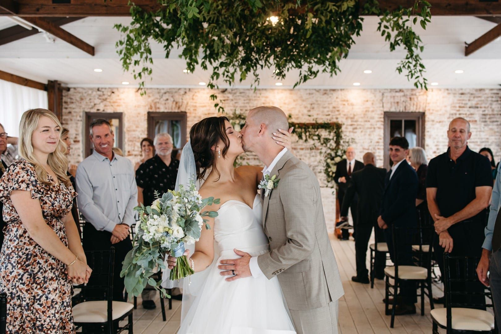 A bride and groom kissing in front of their wedding guests.