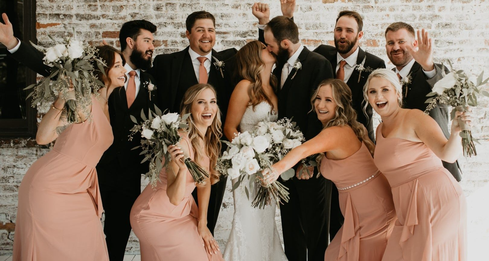 A bride and groom are posing for a picture with their wedding party.