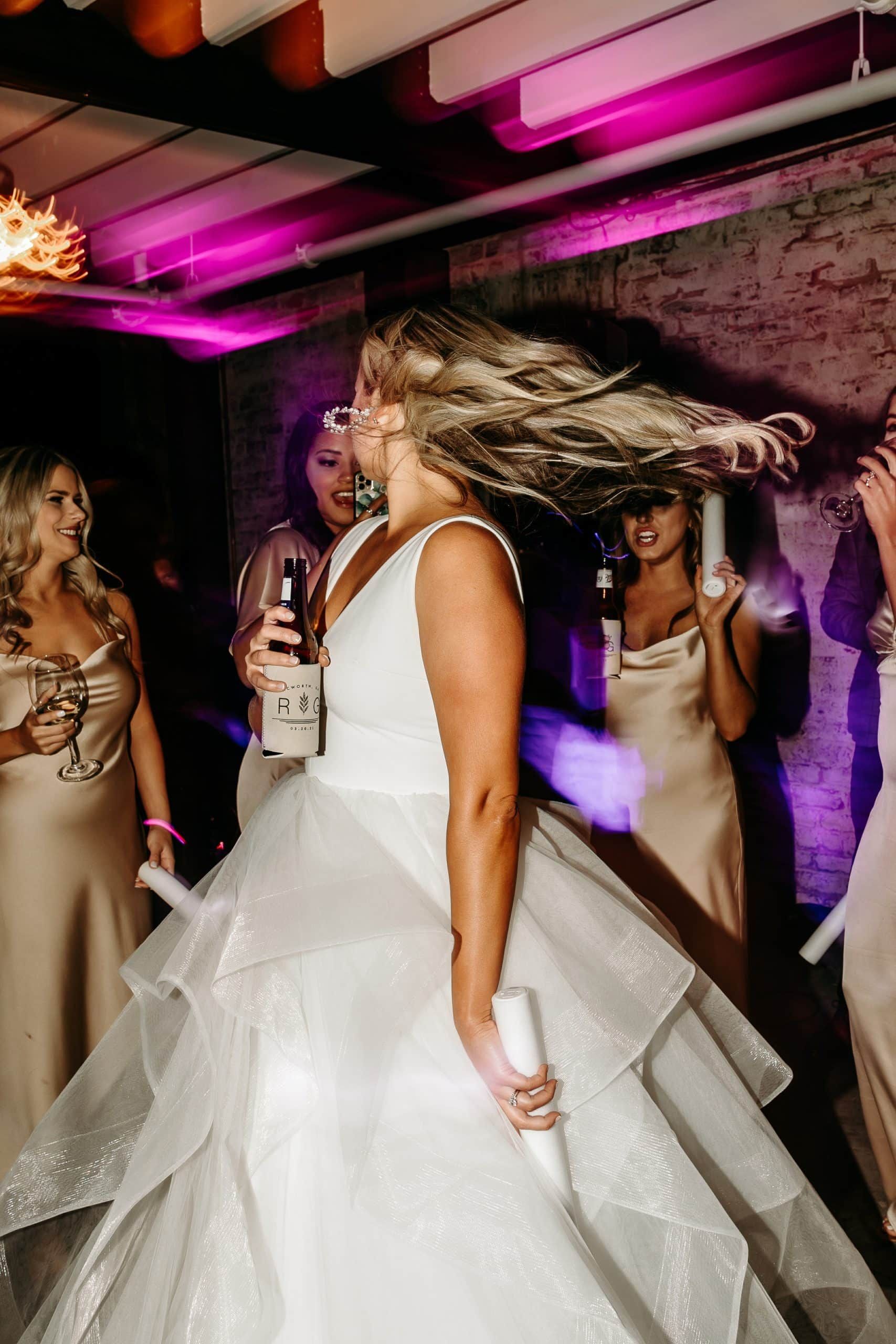 A woman in a wedding dress is dancing at a wedding reception.