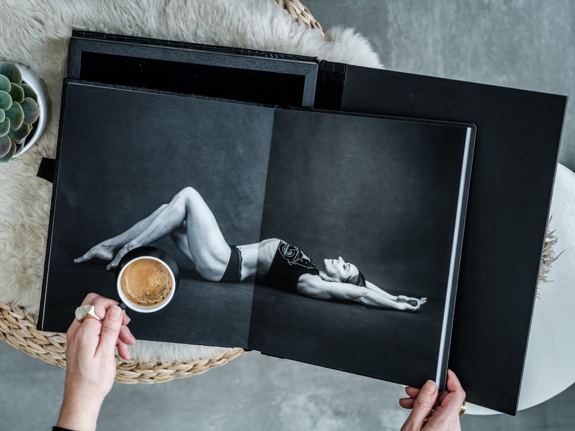 A woman's hands holding a coffee cup and a book in a photo gallery.