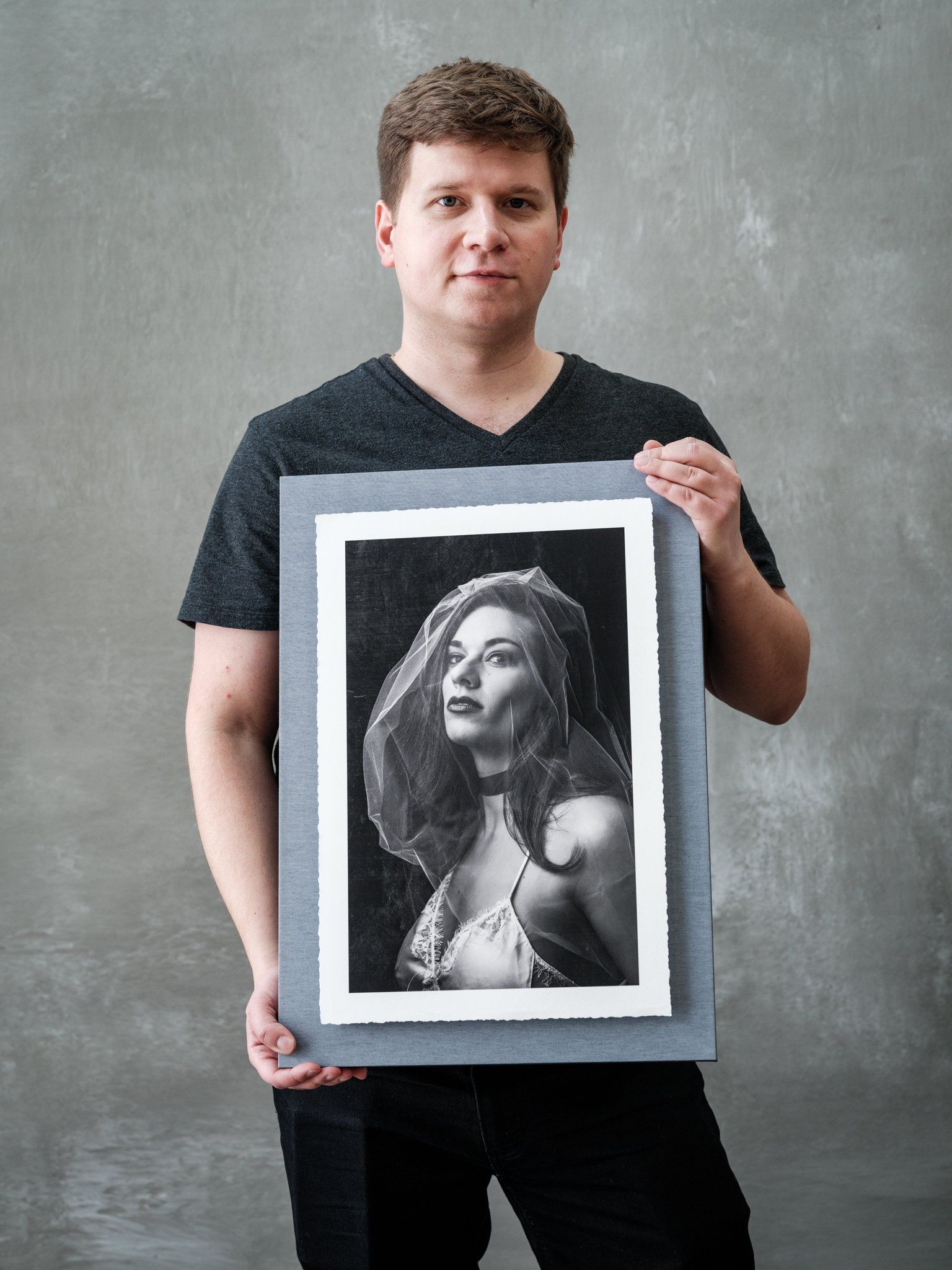 A man holding a framed photo of a woman