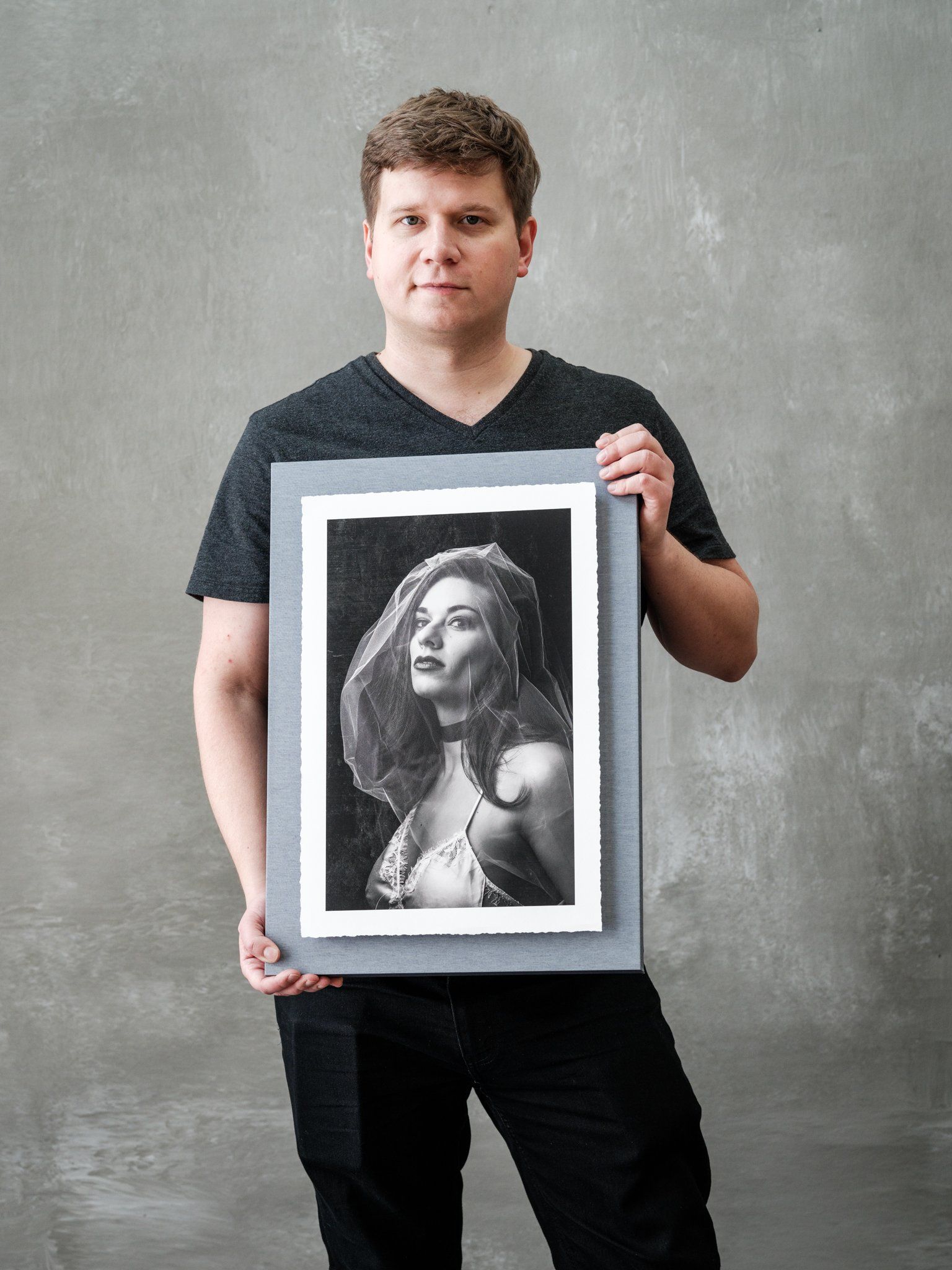 A man holding a framed photo of a woman