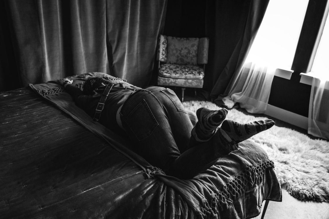 sexy boudoir shot of woman lying on bed fully clothed