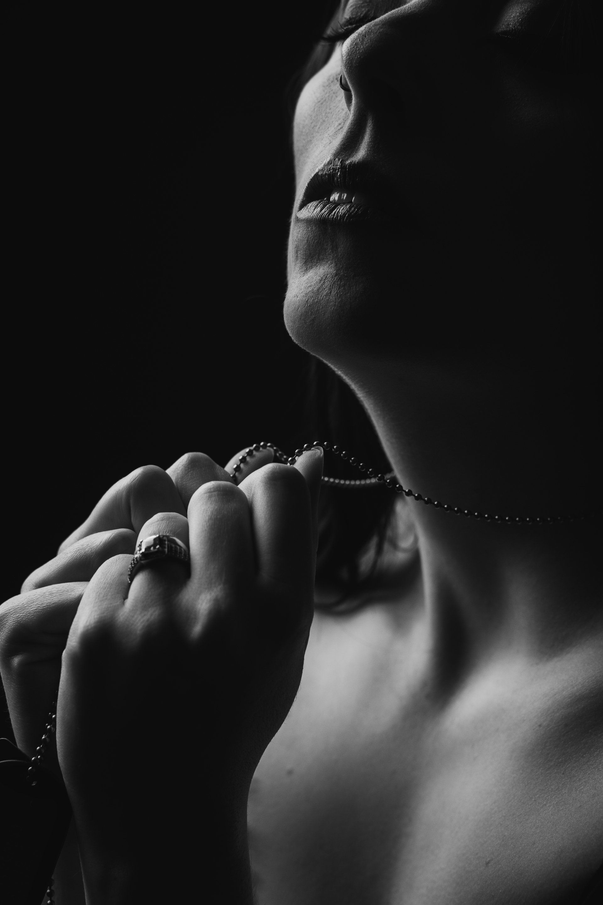 portrait of woman holding necklace with eyes closed