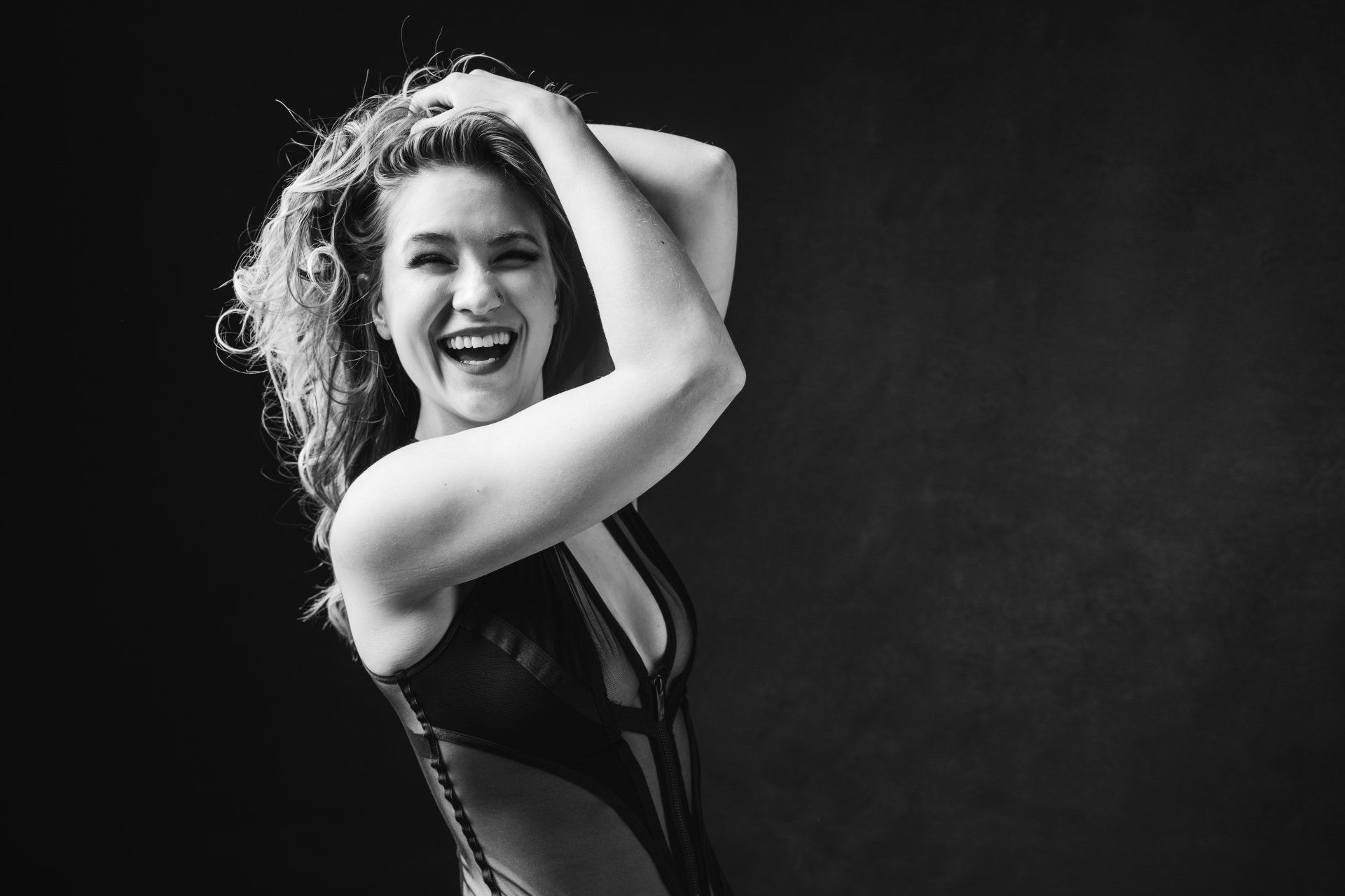 boudoir portrait of woman smiling with hands in hair