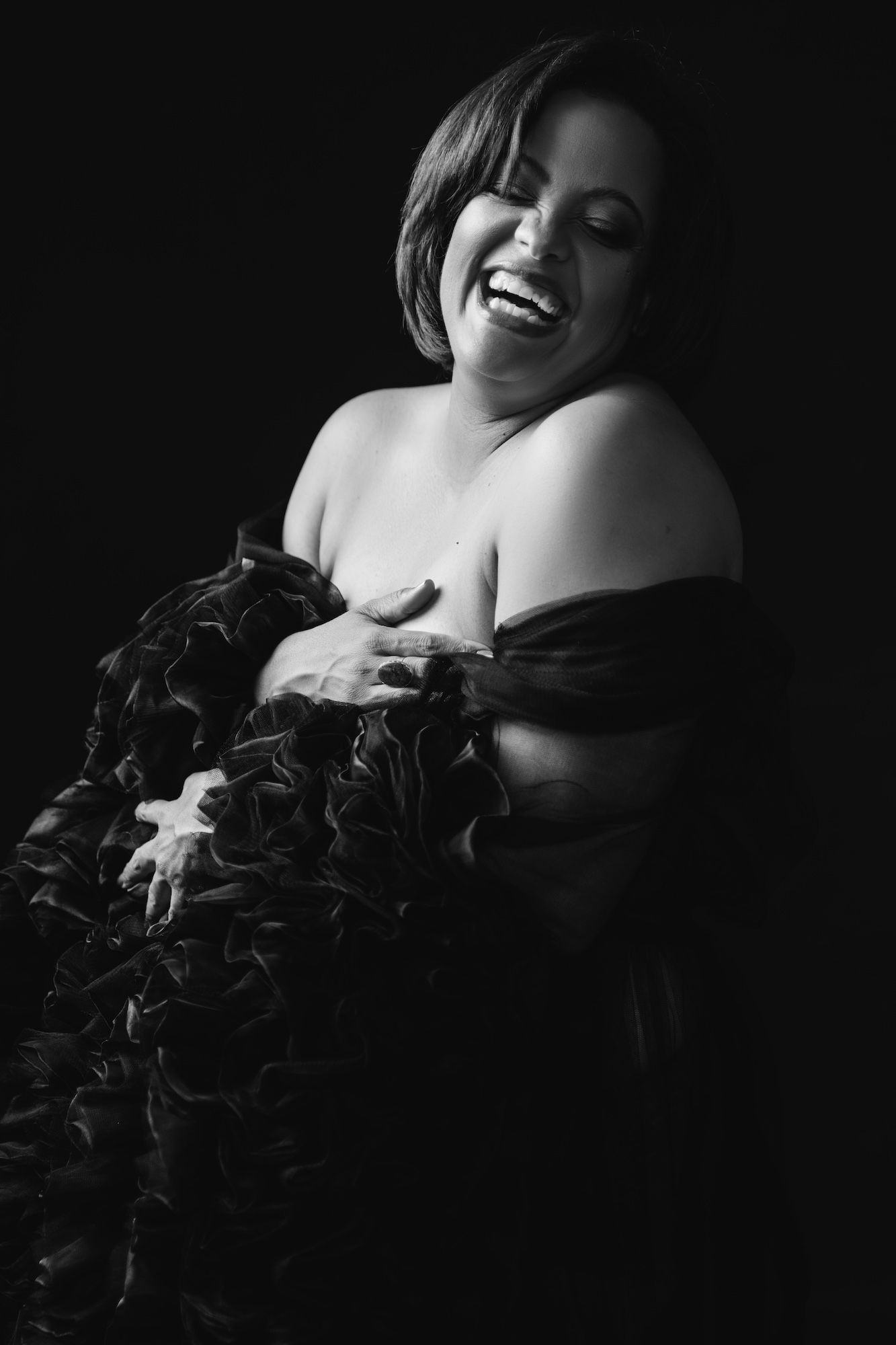 A woman in a black gown smiles, enjoying herself.