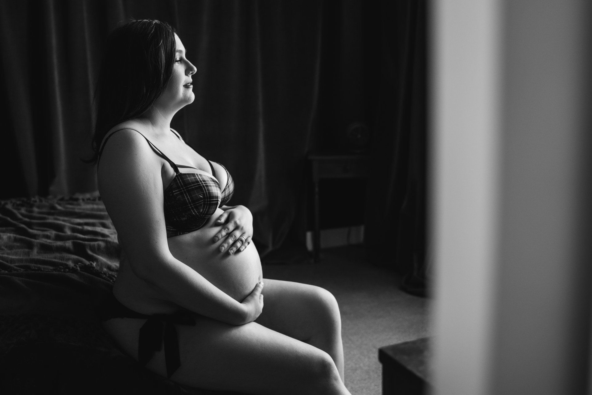 woman sitting on bed holding pregnant belly