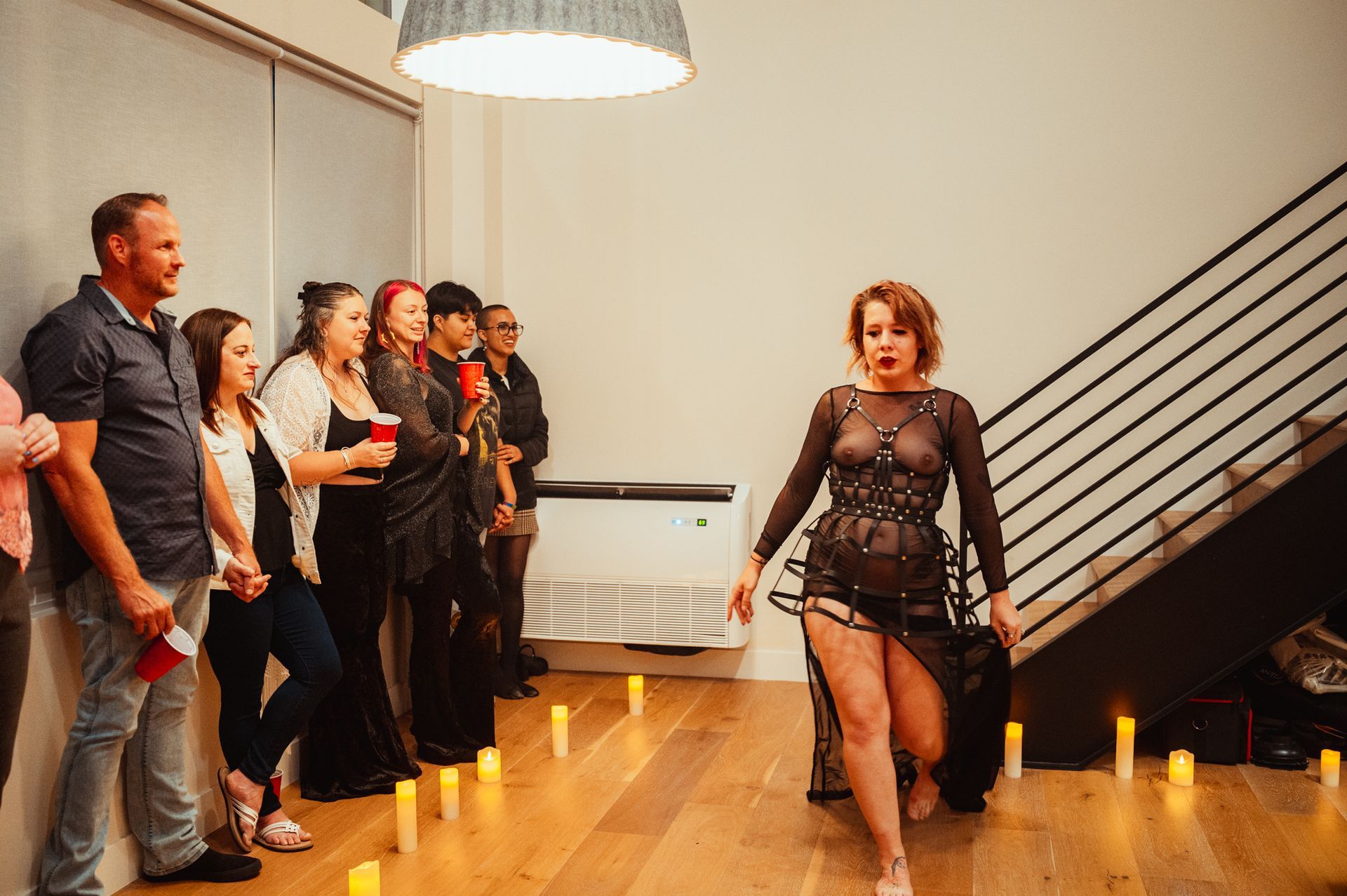 A woman in a sleek black dress walks along a hallway, embodying sophistication and grace in her stride.