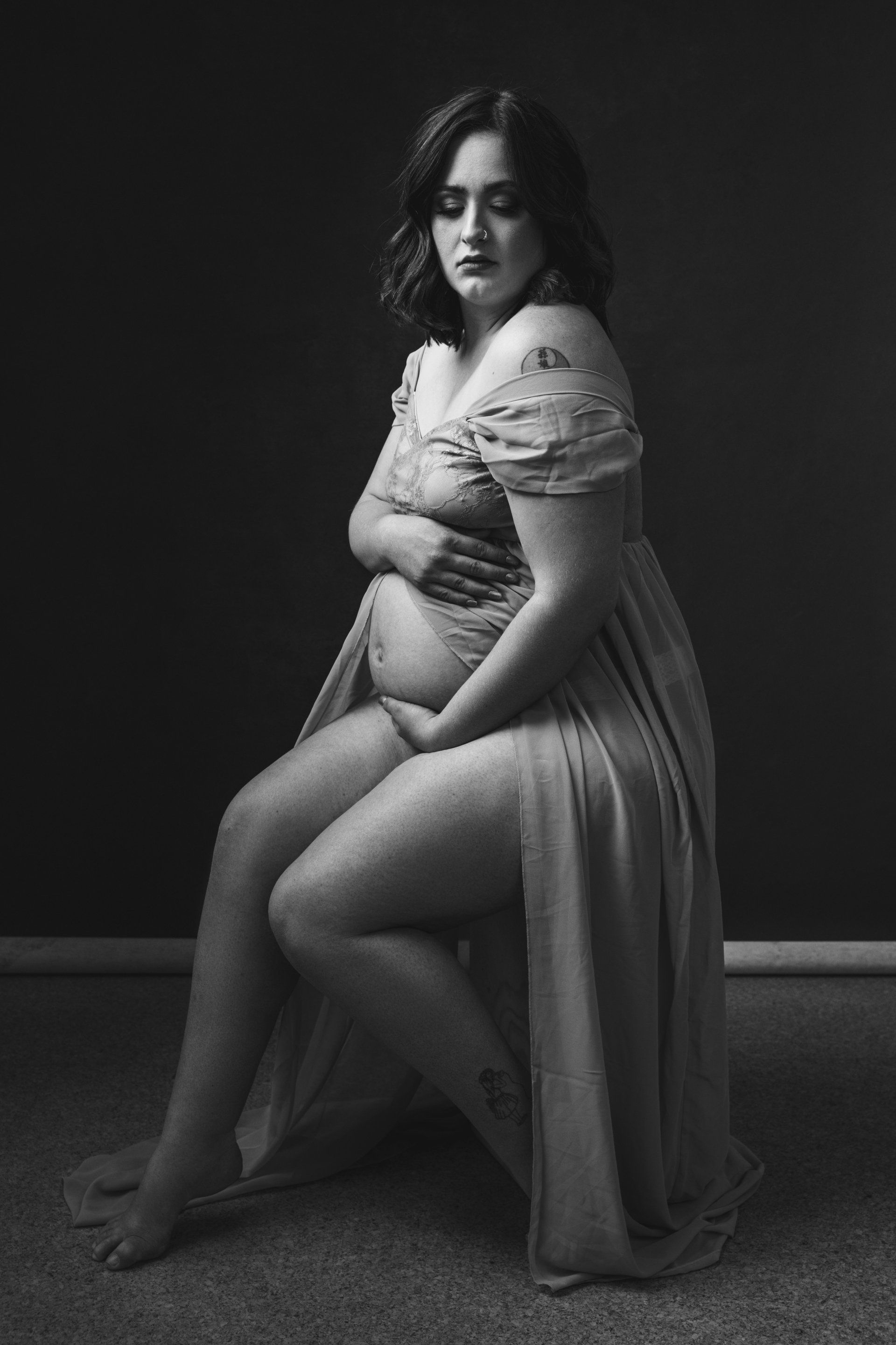 A woman in a dress, pregnant, sitting on the chair