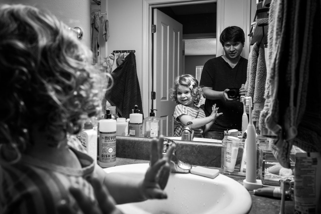 A father and daughter in a bathroom, engaging in hygiene practices.