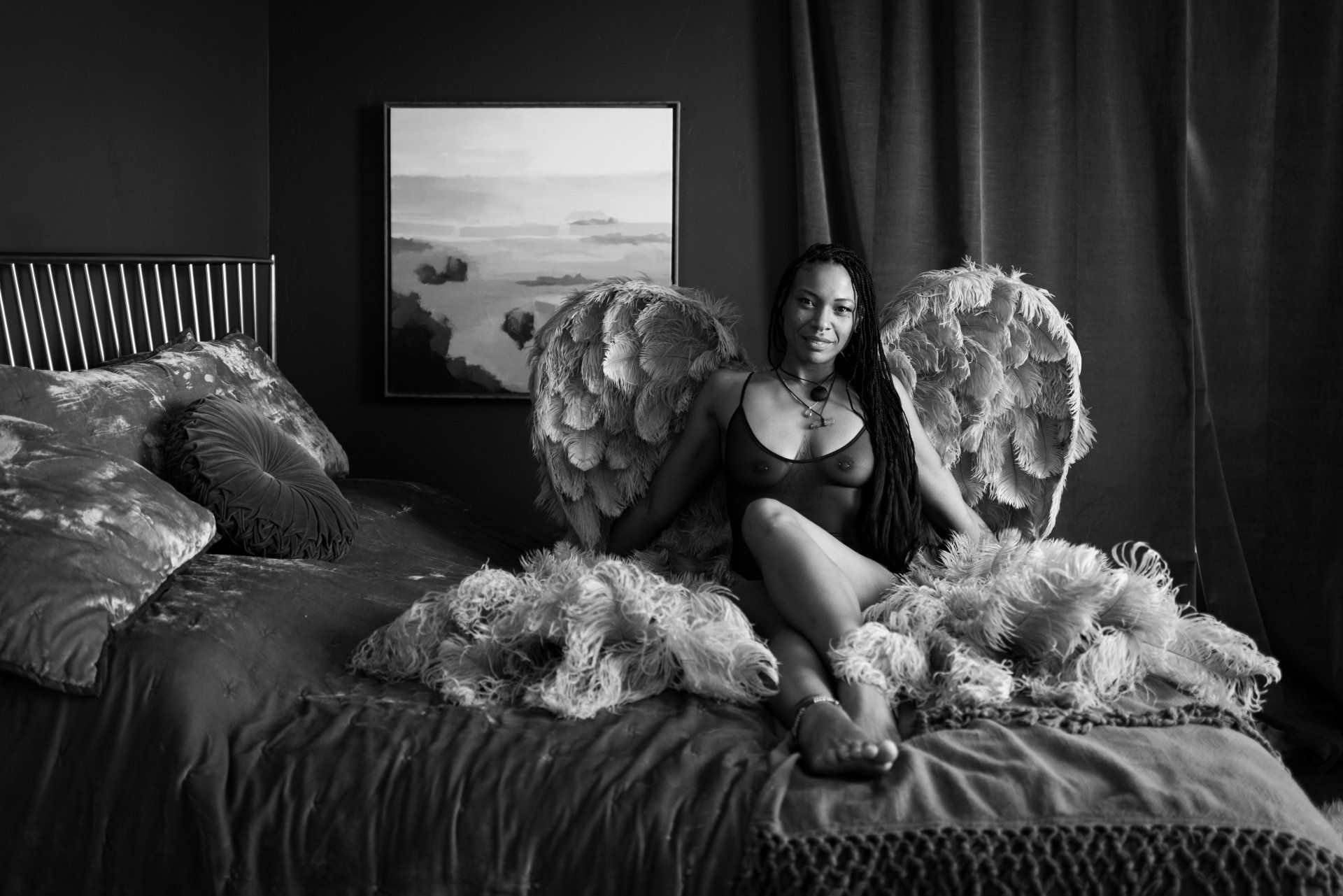 woman wearing large wings sitting on bed