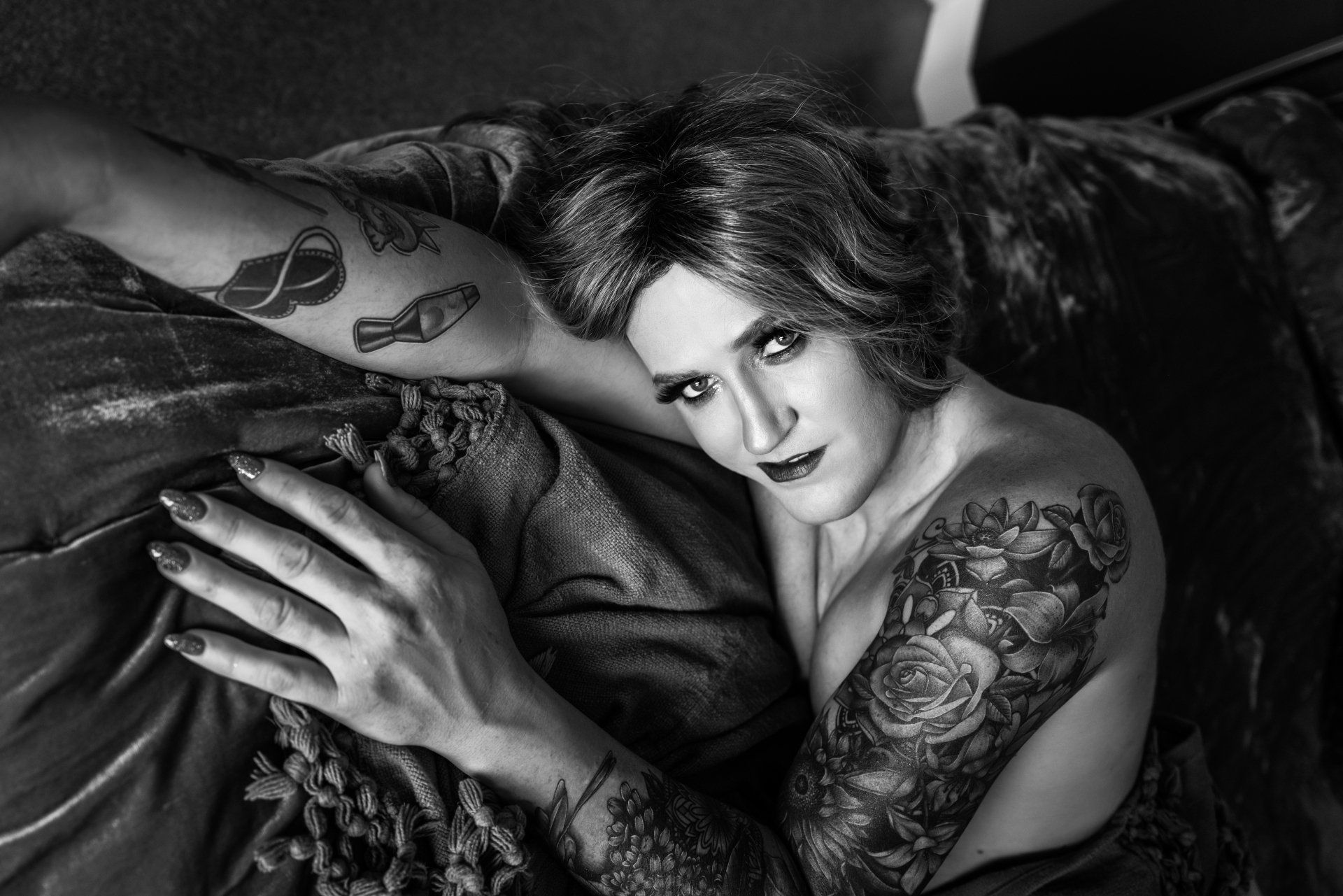 A tattooed woman lying on a bed.