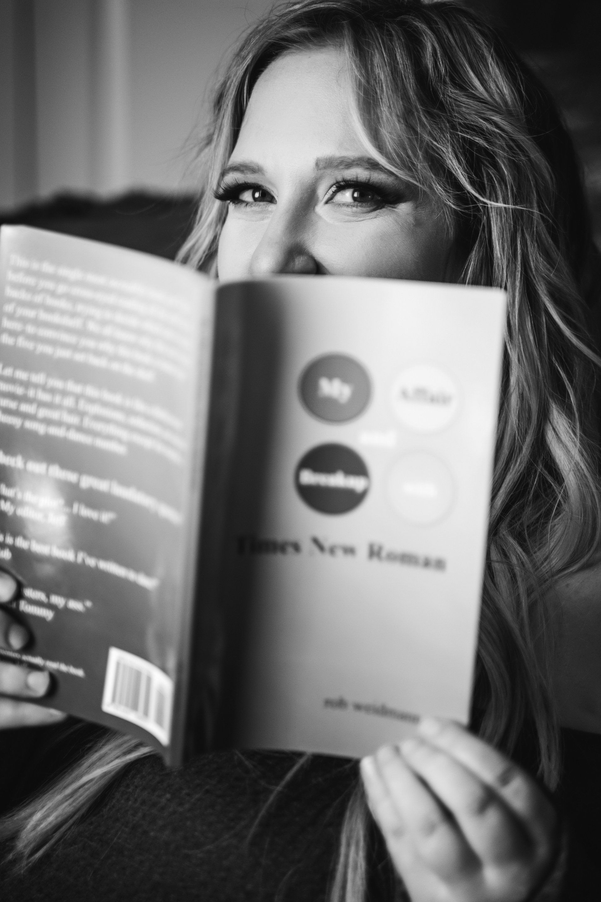 portrait of woman peeking over book and smiling