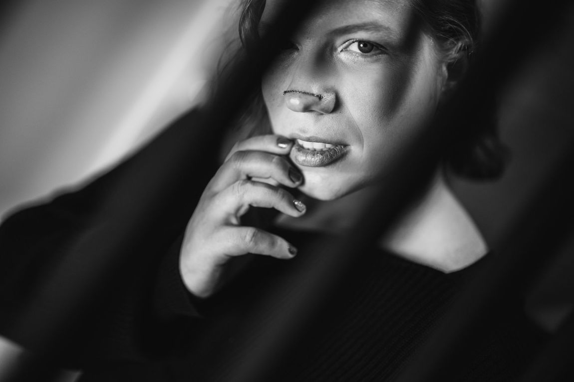 A black and white portrait of a woman thoughtfully resting her chin on her hand, exuding a contemplative expression.