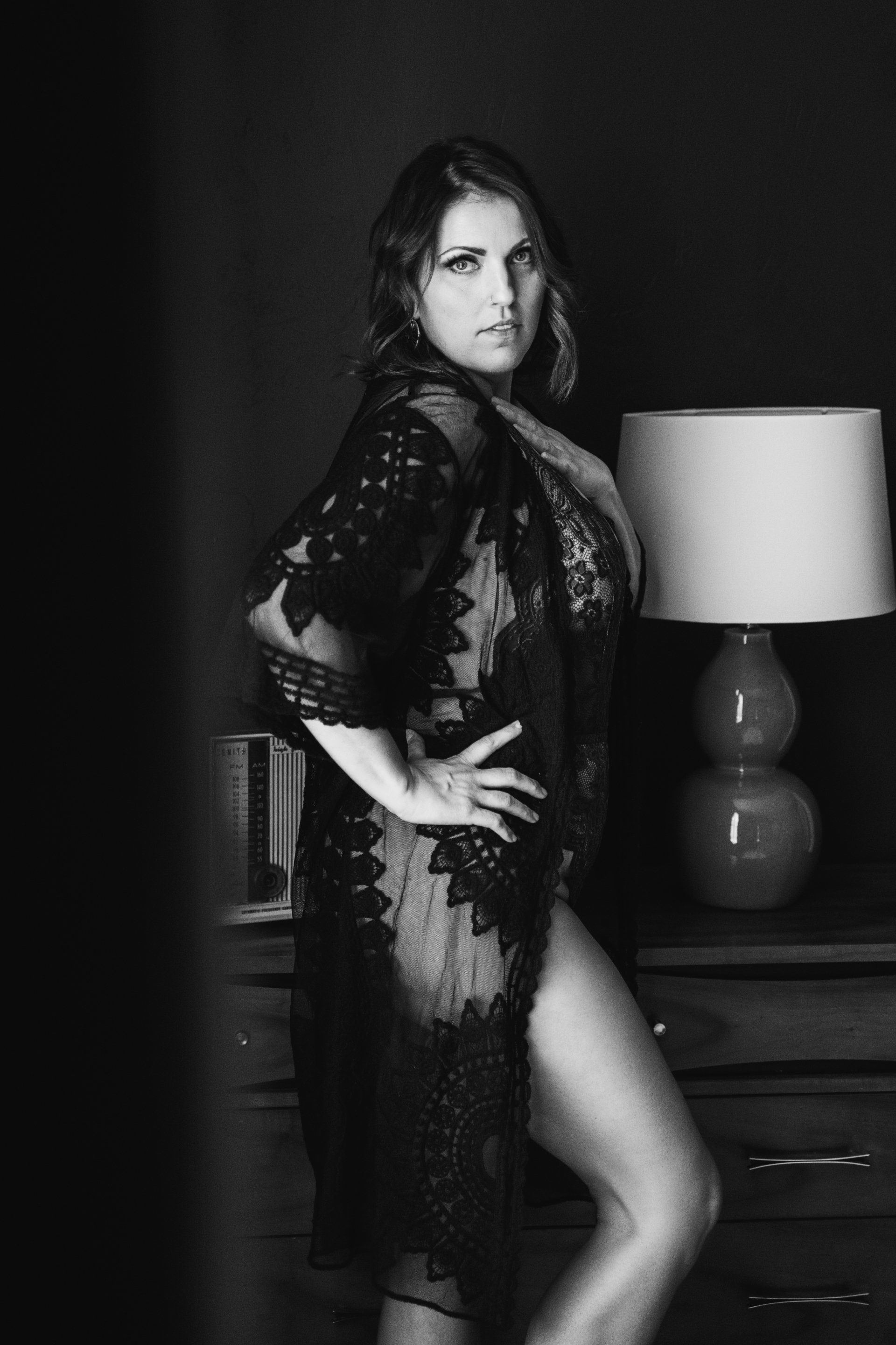 black and white boudoir image of woman standing in lace robe